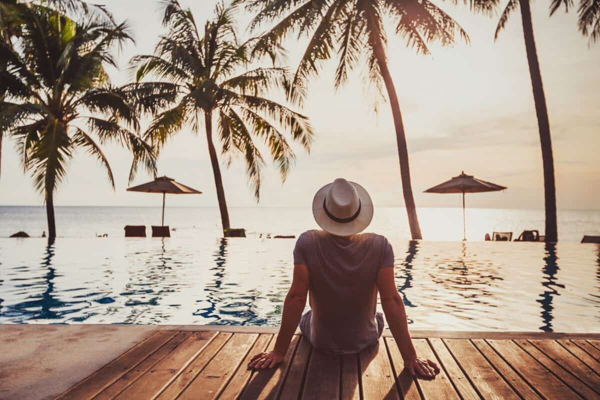 Image of a man sitting by a beachside infinity pool watching the sunrise